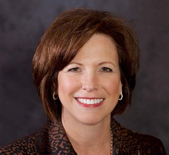 A woman sitting on a stool next to a podium